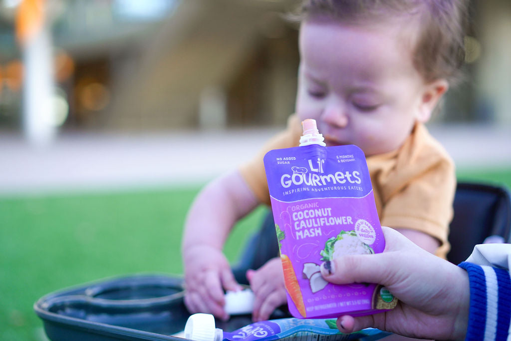 Baby sitting in a high chair with Lil' Gourmets Coconut Cauliflower Mash